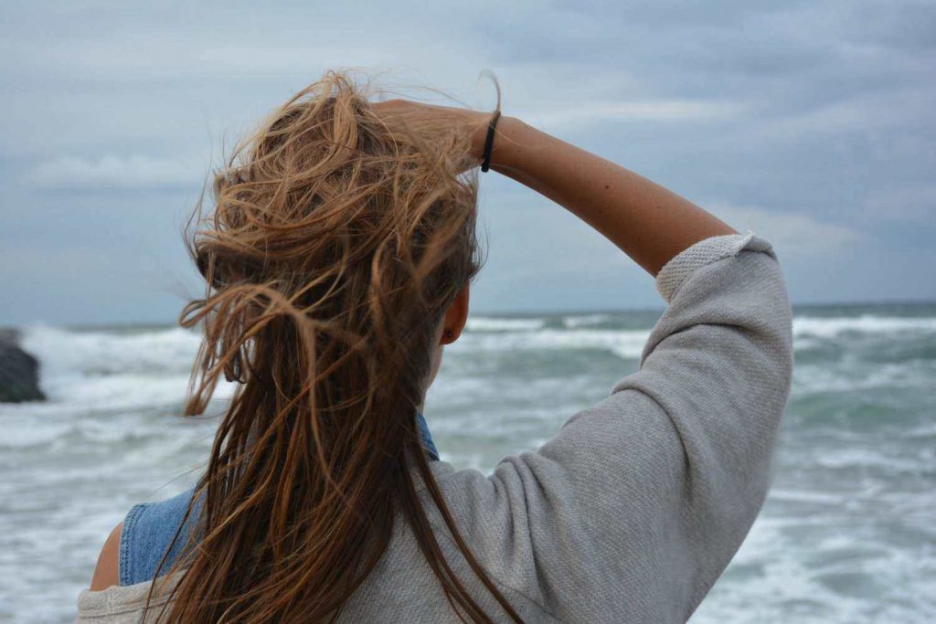 Woman looking out over beach at waves